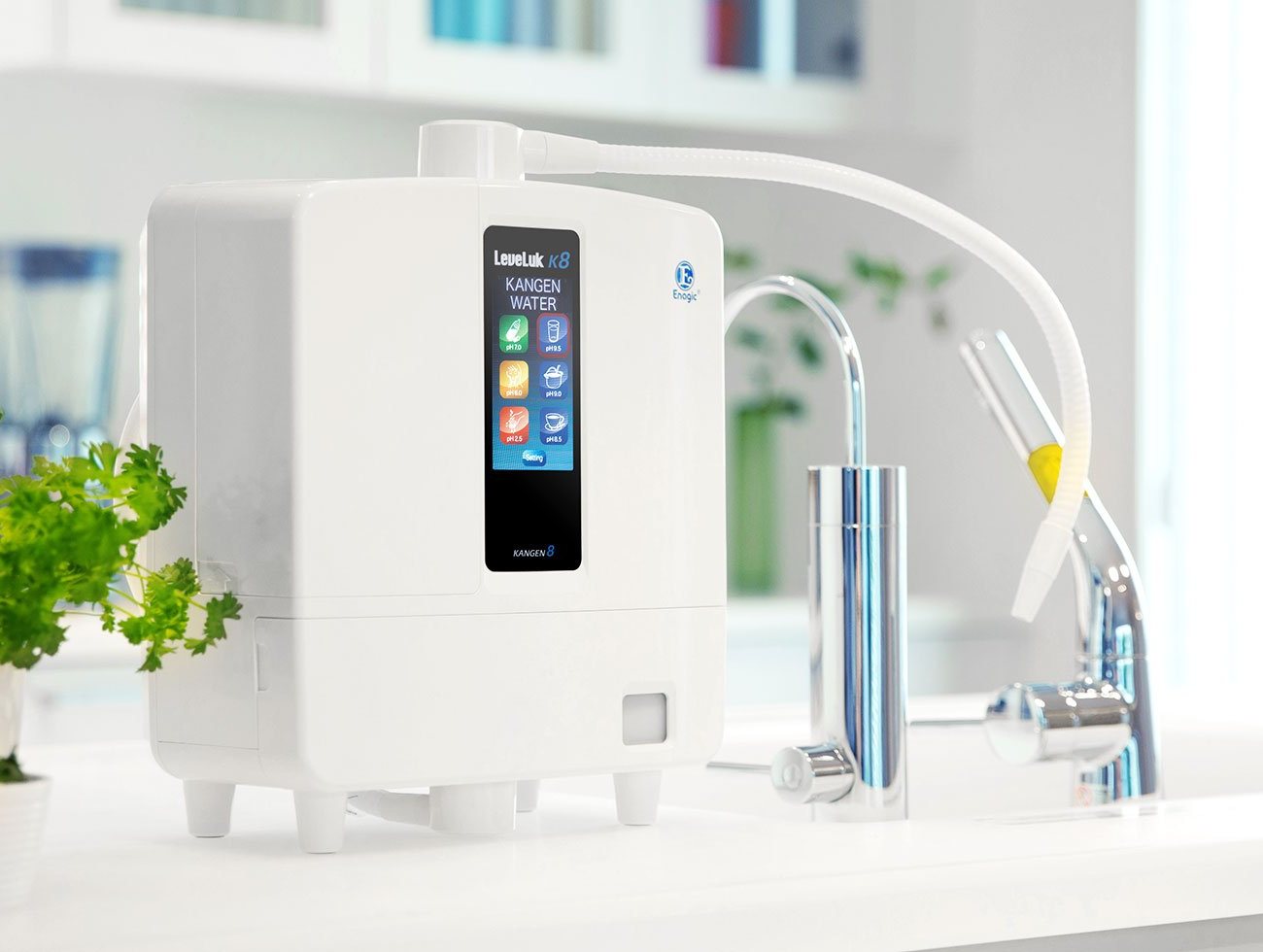 Sistema Kangen K8 sobre la encimera de una cocina blanca, junto al grifo